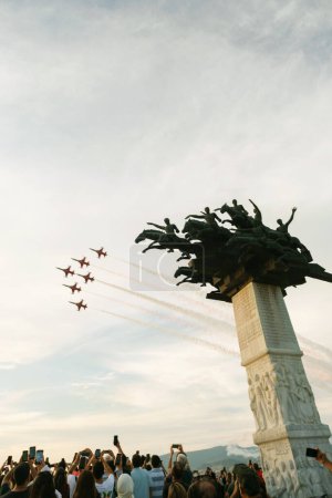Photo for Izmir, Turkey, September 9, 2023: The acclaimed Turkish Stars fighter jets soar past the iconic Republic Tree Monument while an enthralled crowd captures the breathtaking display on their smartphones, immortalizing a moment of national pride - Royalty Free Image