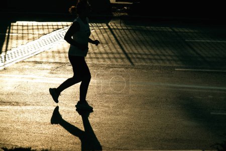 Téléchargez les photos : Izmir, Turquie, 10 septembre 2023 : Les coureurs deviennent des silhouettes contre la lumière du soleil sur l'asphalte pendant le marathon d'Izmir - en image libre de droit