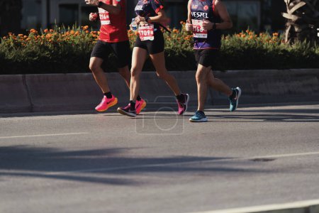 Téléchargez les photos : Izmir, Turquie, 10 septembre 2023 : Un gros plan dynamique capture la foulée et les chaussures d'athlétisme de trois coureurs de marathon, mettant en vedette une femme et deux hommes - en image libre de droit