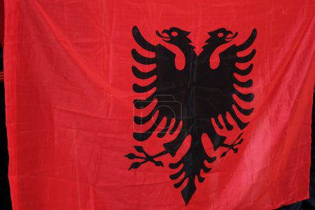 Foto de Una foto de cerca que captura los detalles de la bandera albanesa en la mano, mostrando su diseño distintivo y colores vibrantes. - Imagen libre de derechos