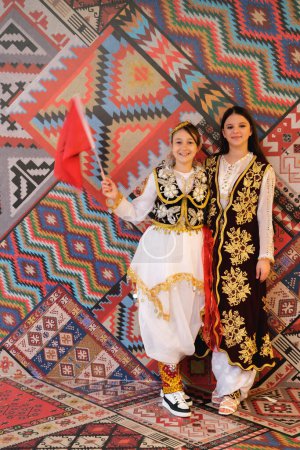 Téléchargez les photos : Tirana, Albanie - 28 novembre : Deux filles avec des drapeaux albanais posent devant les motifs traditionnels au Palais des Congrès pendant la fête de l'indépendance - en image libre de droit