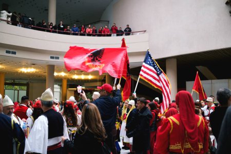 Foto de Tirana, Albania - 28 de noviembre: Danza tradicional albanesa con banderas albanesas y americanas, cerca de la estatua de la Madre Teresa en el Palacio - Imagen libre de derechos
