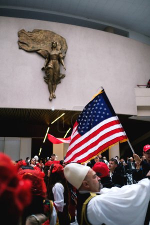 Téléchargez les photos : Tirana, Albanie - 28 novembre : Danse traditionnelle albanaise avec des drapeaux albanais et américains, près de la statue de Mère Teresa au Palais - en image libre de droit