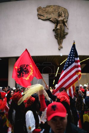 Foto de Tirana, Albania - 28 de noviembre: Danza tradicional albanesa con banderas albanesas y americanas, cerca de la estatua de la Madre Teresa en el Palacio - Imagen libre de derechos
