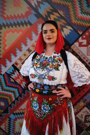 Foto de Tirana, Albania - 28 de noviembre: Una mujer vestida con ropa tradicional albanesa posa sola sobre un telón de fondo con patrones tradicionales albaneses - Imagen libre de derechos