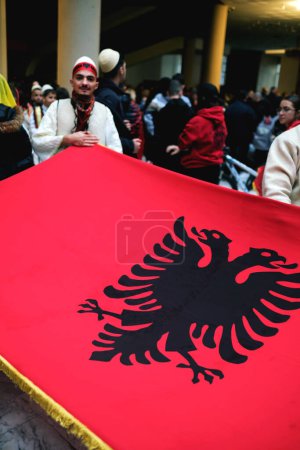 Foto de Tirana, Albania - 28 de noviembre: Un primer plano de un albanés sosteniendo la bandera nacional en el Palacio de la Madre Teresa durante el Día de la Independencia - Imagen libre de derechos