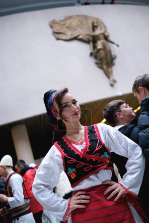 Foto de Tirana, Albania - 28 de noviembre: Una estudiante vestida con el traje tradicional albanés posa frente a la estatua de la Madre Teresa en el Palacio - Imagen libre de derechos