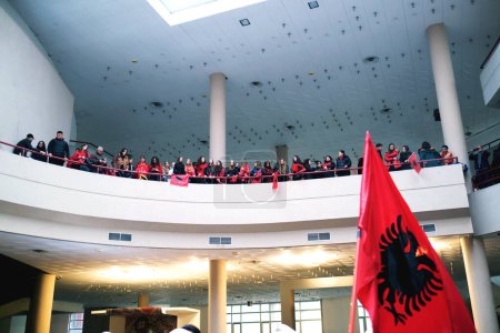 Photo for Tirana, Albania - November 28: Crowd on the balcony with flags watching the event, Albanian flag visible below at the Palace of the congresse - Royalty Free Image