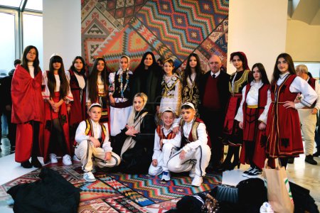 Photo for Tirana, Albania - November 28: A group of Albanian citizens, including students and teachers, pose in front of a traditional patterned backdrop - Royalty Free Image