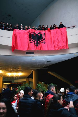 Foto de Tirana, Albania - 28 de noviembre: las multitudes celebran el Día de la Independencia en el Palacio Madre Teresa con una gran bandera albanesa en el balcón. - Imagen libre de derechos