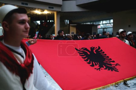 Foto de Tirana, Albania - 28 de noviembre: Un primer plano de un albanés sosteniendo la bandera nacional en el Palacio de la Madre Teresa durante el Día de la Independencia - Imagen libre de derechos