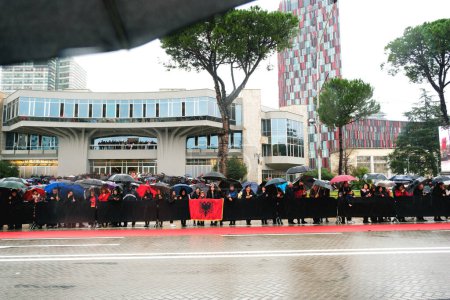 Téléchargez les photos : Tirana, Albanie - 28 novembre 2023 : Par un jour pluvieux de l'indépendance, les citoyens avec des drapeaux albanais et des parapluies regardent le défilé du bord de la route à l'avenue des martyrs de la nation Boulevard avenue des martyrs de la nation - en image libre de droit