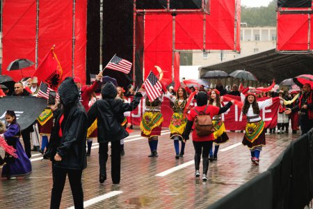 Photo for Tirana, Albania - November 28, 2023: On Avenue of Martyrs of the Nation, students in traditional costumes march with Albanian and American flags on a rainy Independence Day. - Royalty Free Image