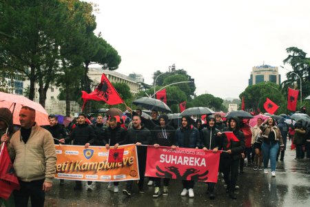 Photo for Tirana, Albania - November 28, 2023: Along Avenue of Martyrs of the Nation, people joyfully participate in an Independence Day march on a rainy day, holding Albanian flags with smiling faces. - Royalty Free Image