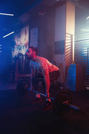 Photo for Athlete perfecting the deadlift in a mystical gym ambiance, with blue and red lighting cutting through the mist - Royalty Free Image