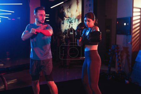 Woman and man training kick box at gym.