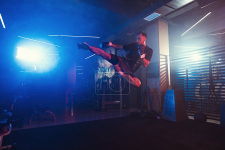 Une puissante performance de kickboxing sous des lumières brumeuses et colorées dans la salle de gym