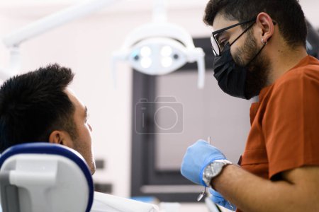 Téléchargez les photos : Un dentiste en profonde concentration alors qu'il examine son patient, fournissant des soins d'expert avec une précision qui assure un sourire sain - en image libre de droit