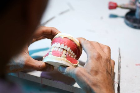 Téléchargez les photos : Gros plan de l'artisanat dentaire prothétique, mettant en valeur le travail détaillé de création d'une prothèse dentaire - en image libre de droit