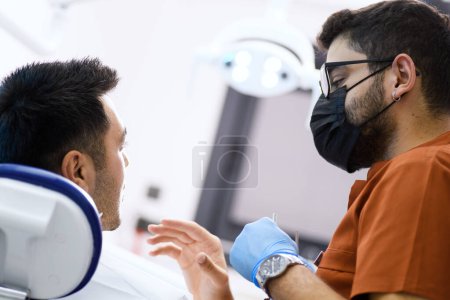 Téléchargez les photos : Un dentiste en profonde concentration alors qu'il examine son patient, fournissant des soins d'expert avec une précision qui assure un sourire sain - en image libre de droit