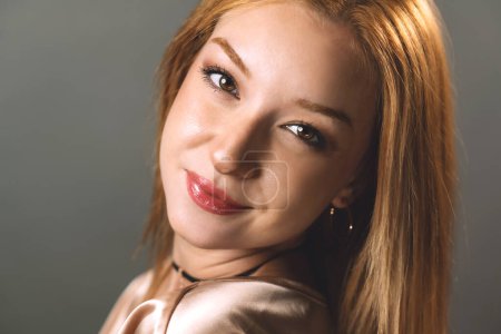A portrait of a young blonde woman with a warm, inviting smile, exuding casual elegance.
