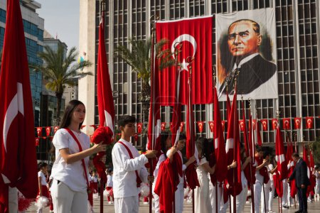 Téléchargez les photos : Izmir, Turquie - 23 avril 2024 : Une assemblée solennelle d'enfants avec des drapeaux turcs lors de la cérémonie de la Journée nationale de la souveraineté et de l'enfance, avec une grande bannière Ataturk supervisant la place de la République. - en image libre de droit