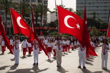 Photo for Izmir, Turkey - April 23, 2024: Youth march with Turkish flags at the National Sovereignty and Children's Day celebrations, with the Swissotel in the background - Royalty Free Image