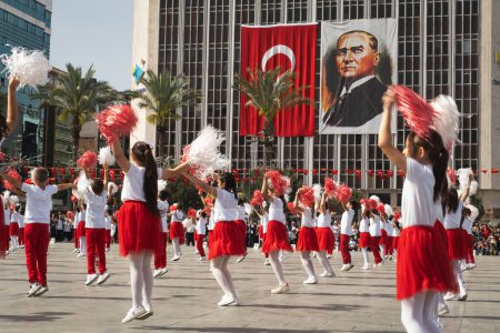 Photo for Izmir, Turkey April 23, 2024 Joyful dance by children in red and white, with Turkish flags and Atatrk's portrait adorning the backdrop, during National Sovereignty and Children's Day. - Royalty Free Image