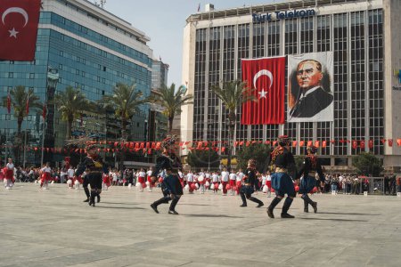 Photo for Izmir, Turkey - April 23, 2024: Children dressed in traditional Zeybek attire perform the iconic dance at Republic Square for the National Sovereignty and Children's Day, with a backdrop of Turkish flags and an Ataturk portrait - Royalty Free Image