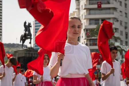 Téléchargez les photos : Izmir, Turquie - 23 avril 2024 : Vue rapprochée d'un jeune étudiant tenant un drapeau turc, avec d'autres participants agitant des drapeaux en arrière-plan, lors des célébrations de la Journée nationale de la souveraineté et de l'enfance du 23 avril sur la place de la République d'Izmir - en image libre de droit