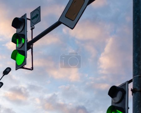 Traffic lights with green color background of clouds at sunset