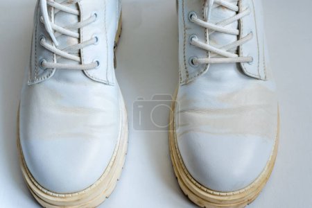 Foto de White leather boots with yellow stains on white background - Imagen libre de derechos