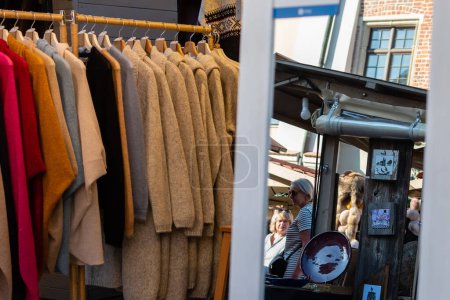 Women's coat store at open-air fair with mirror and reflections of customers in it