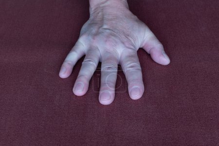 Wrist of right hand of an elderly man close-up on dark fabric