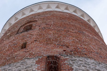 Amplia torre de ladrillo rojo con ventanas en el casco antiguo. Vista de abajo hacia arriba