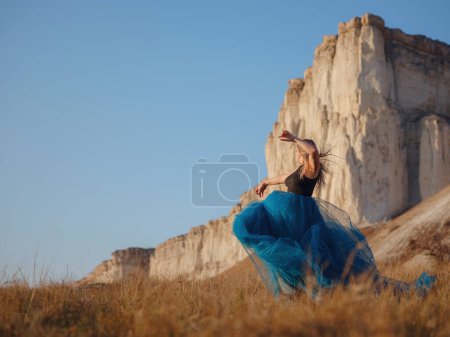 Photo for Fashionable woman on desert field near mountain wearing black top and blue tulle skirt. Wild west. Summer holidays dance. Beautiful and sexy plus size model - Royalty Free Image