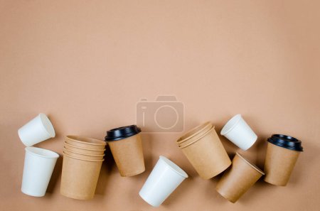Top view on different eco-friendly disposable paper cups on beige background. Paper food packaging and wooden cutlery. Street food paper packaging from natural material. 