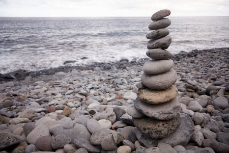 Photo for Tall balanced pile of pebble stones on a stony beach in Madeira, Portugal. - Royalty Free Image