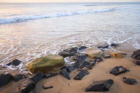 Steiniger Strand und Meer in Porto Santo, Madeira, Portugal. Schwarze Steine auf Sand.
