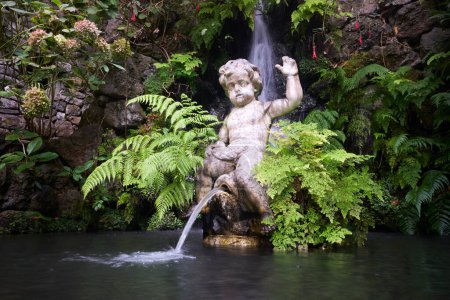 Statue eines Jungen, der auf einen Teich im tropischen Garten des Monte Palace pinkelt, Madeira, Portugal.