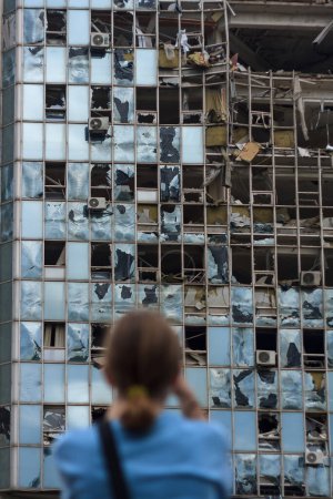 Téléchargez les photos : Fille méconnaissable retour à la caméra se tient devant le bâtiment détruit par un véhicule aérien sans pilote - en image libre de droit