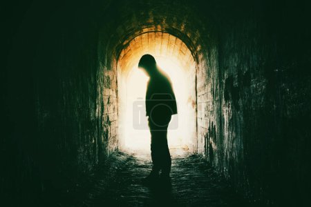 Téléchargez les photos : Silhouette d'un homme dans une hotte dans un tunnel - en image libre de droit