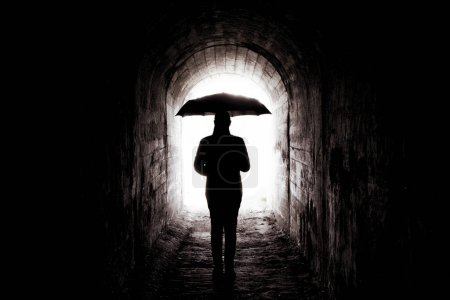 young girl with black umbrella in the tunnel, light at the end of the tunnel