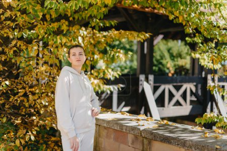 Beautiful elegant woman standing in a park in autumn. autumn yellow leaves. Portrait of joyful woman in park during fall. Happy girl with yellow leaves outdoor. Beauty Romantic Girl Outdoors enjoying