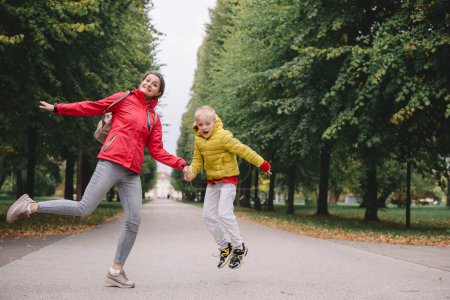 Photo for Mother and son jumping in the autumn park. Fall Season. Happy young beautiful mother and her son have a walk in the park - Royalty Free Image