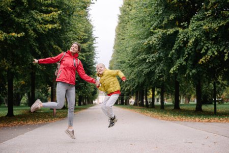 Photo for Mother and son jumping in the autumn park. Fall Season. Happy young beautiful mother and her son have a walk in the park - Royalty Free Image