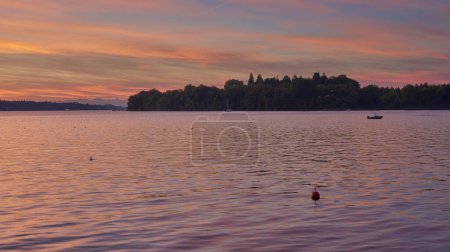 Bodensee Lake Sunrise Panorama. Mañana la luz del sol sobre aguas tranquilas. Presencie el fascinante amanecer sobre el lago Germanys Bodensee, capturado desde un muelle de barcos. Abrace la tranquila belleza de la temprana