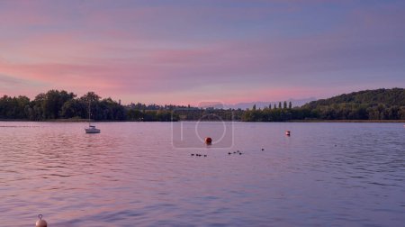 Bodensee Lake Sunrise Panorama. Mañana la luz del sol sobre aguas tranquilas. Presencie el fascinante amanecer sobre el lago Germanys Bodensee, capturado desde un muelle de barcos. Abrace la tranquila belleza de la temprana