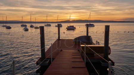 Bodensee Lake Panorama. Evening, twilight, setting sun, picturesque landscape, serene waters, boats and yachts at the dock, beautiful sky with clouds reflecting in the water, riverside at dusk