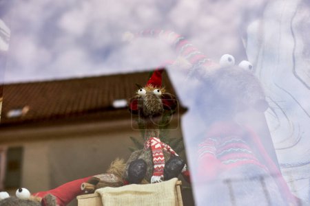 Skurrile Neujahrsmaus in Mütze und Schal steht hinter dem Schaufenster. Ergreifen Sie den Charme der Weihnachtszeit mit diesem entzückenden Bild mit einer Spielzeugmaus oder einer Ratte, die ein lustiges Neujahrsfest trägt